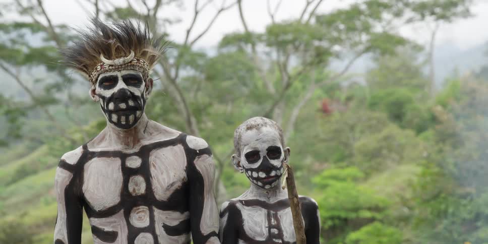 An indigenous man and boy wear skeleton face and body paint