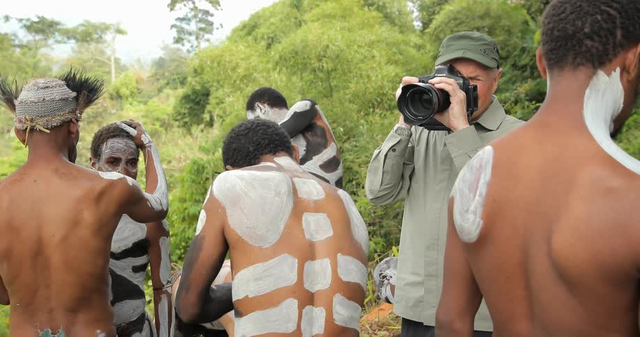 Man taking pictures of local natives who are applying paint