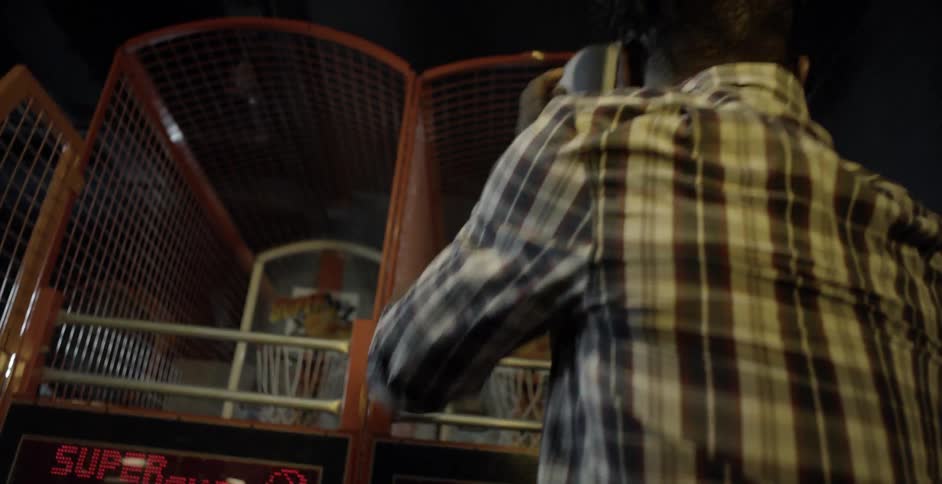 A man and woman shoot basketballs in an arcade
