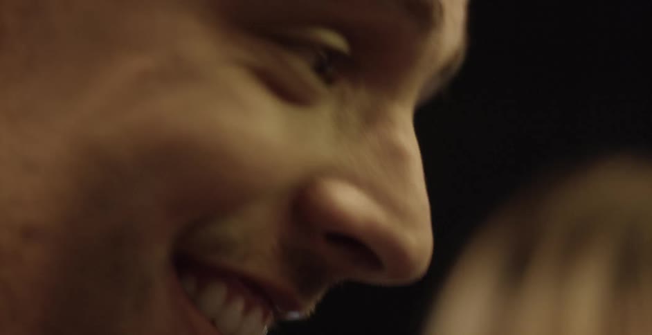 A close up of a young man smiling and shaking his head
