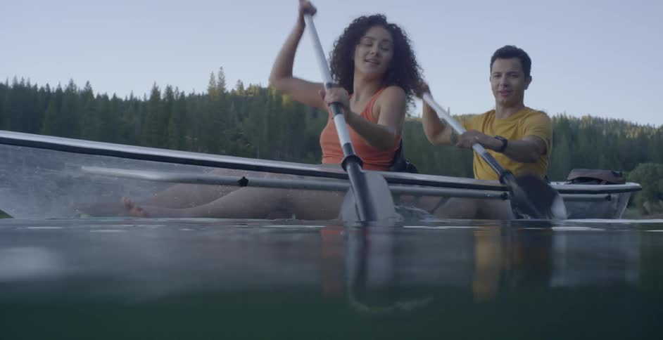 A woman and a man doing synchronized rowing in a transparent canoe