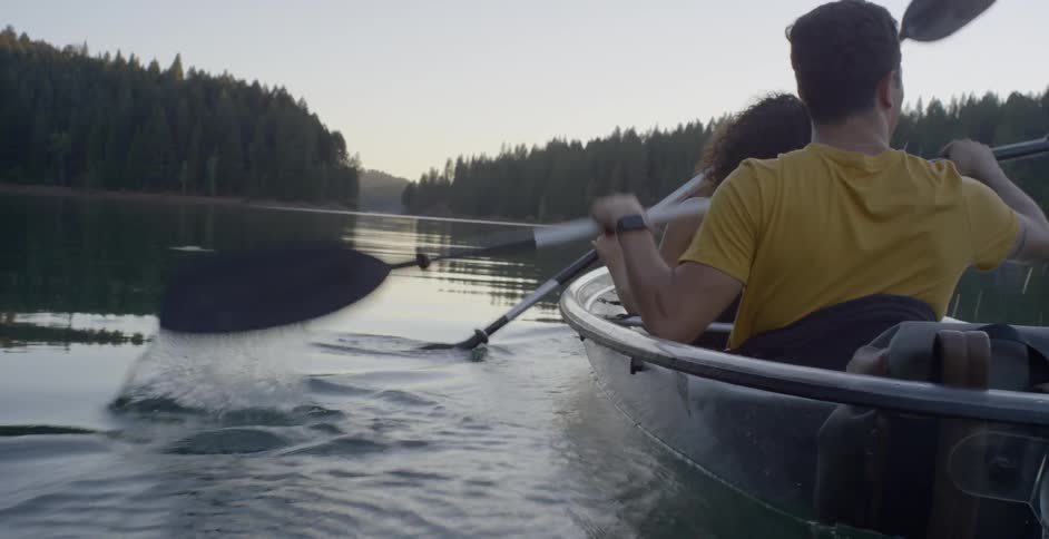 Two people rowing paddles back and forth in a small boat