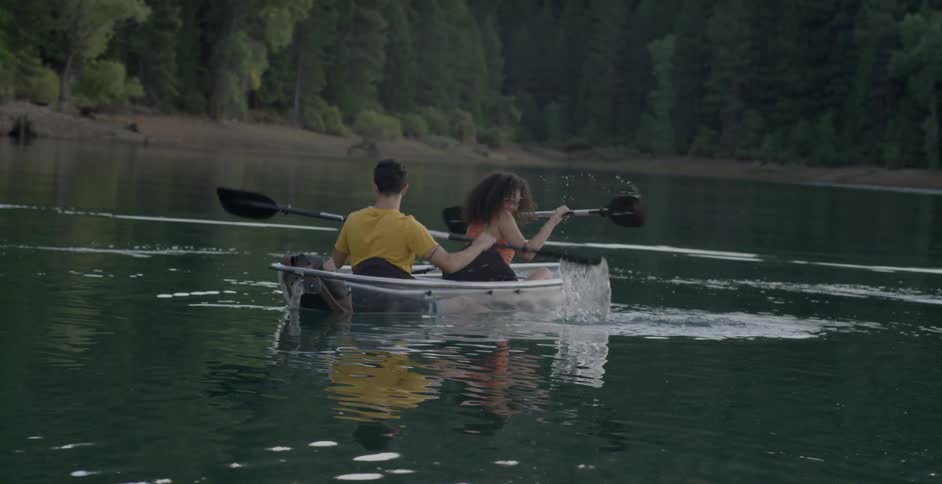 A woman and a man are on a boat rowing down a river