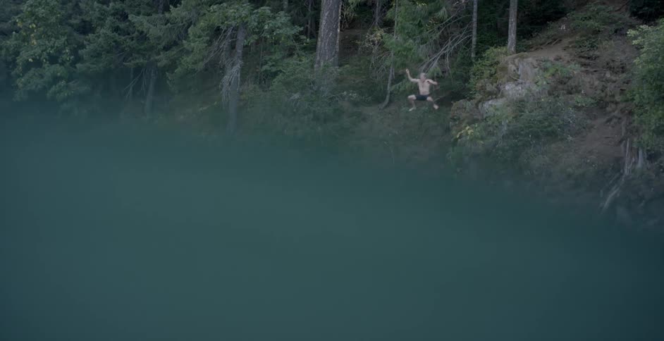 A man dives off the cliff into the lake
