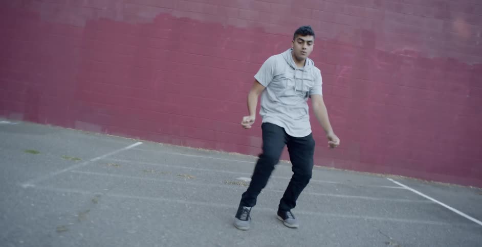 A man dances in a parking lot