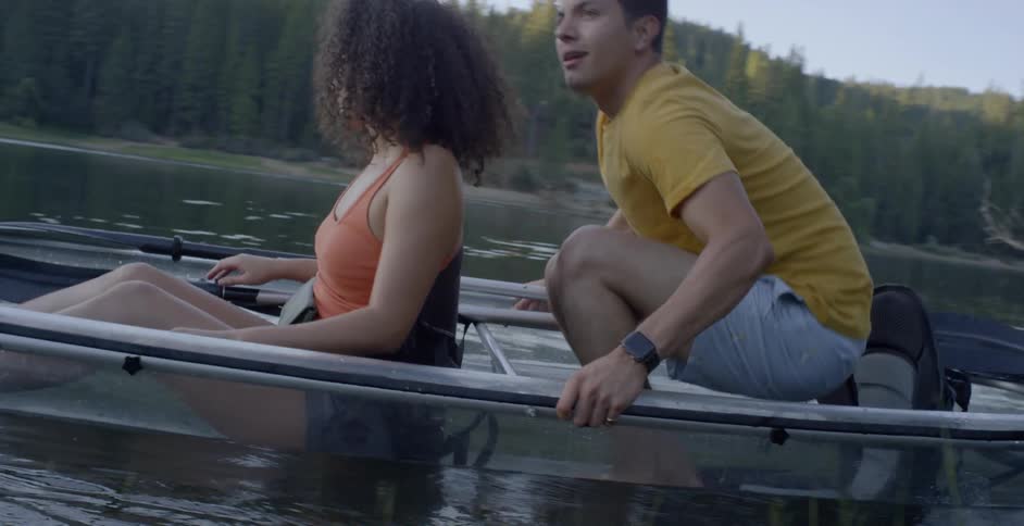 A man pushes a row boat with a woman in it into the water