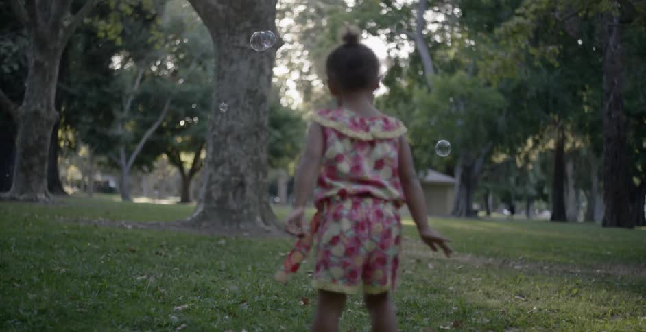 A child chases bubbles in a park