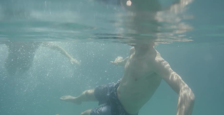 A male caucasian and a female caucasian swimming in water together near a wooded area