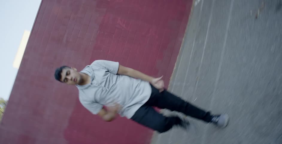A hispanic man dances on in a parking lot