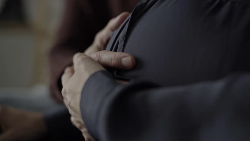 A person with their hands folded over their stomach