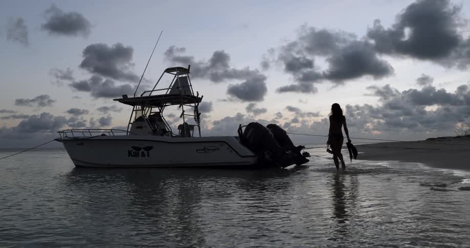A woman walks onto her boat on the shore