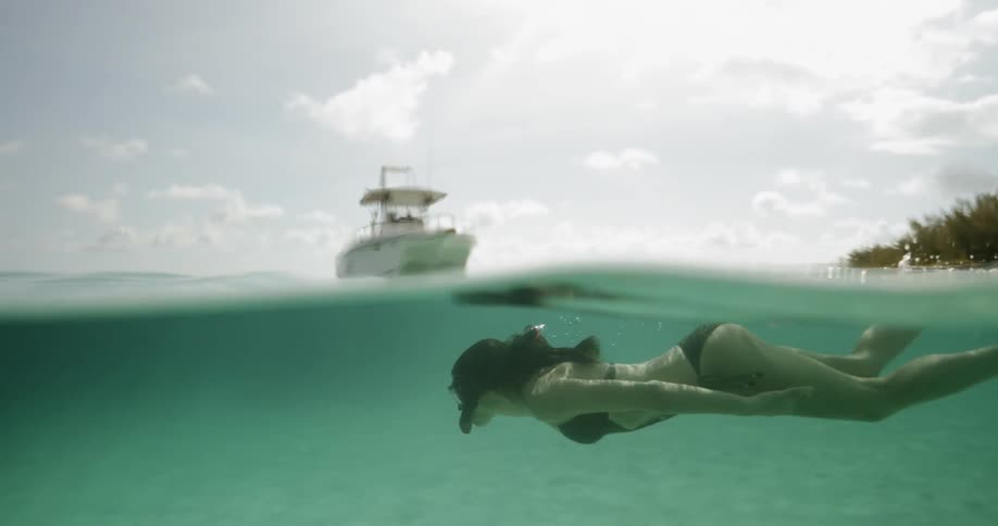 A caucasian female in a bikini snorkeling near a boat