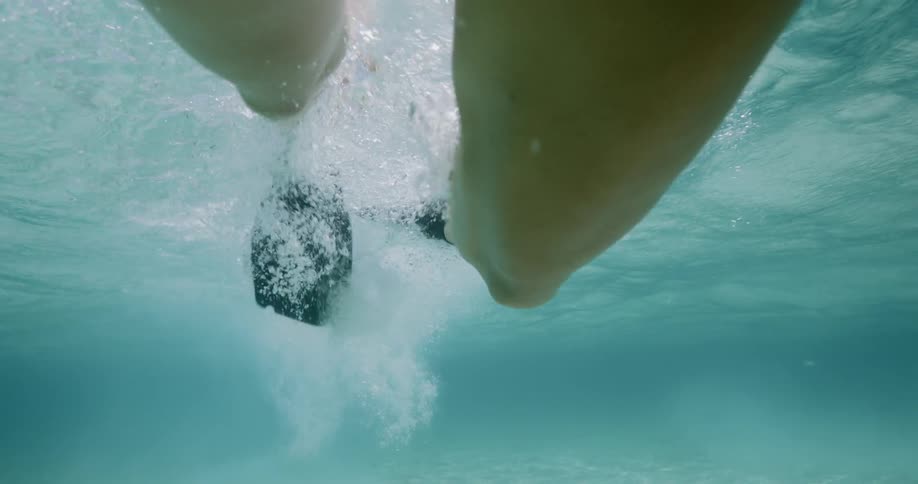 Woman wearing swimming fins swims on seabed during daylight
