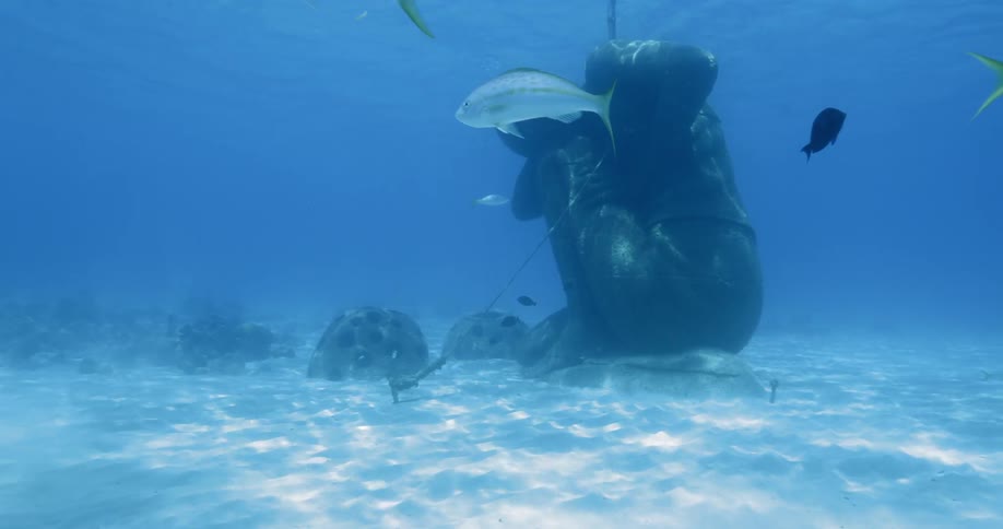An underwater scuba diving sculpture garden surrounded by fish