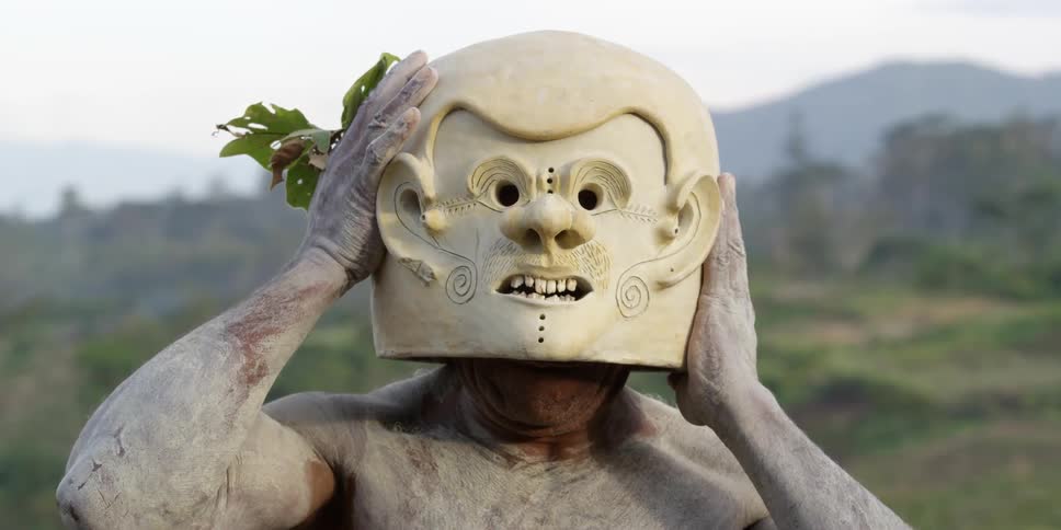 A man puts a hat on in a field