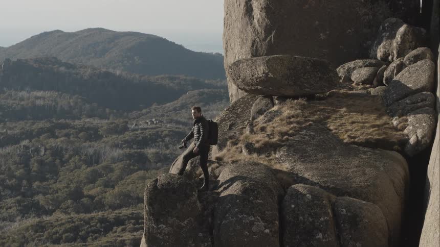 A caucasian male is standing on a rock cliff