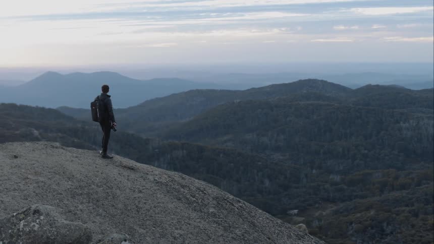 A man with a camera walks along a hilltop
