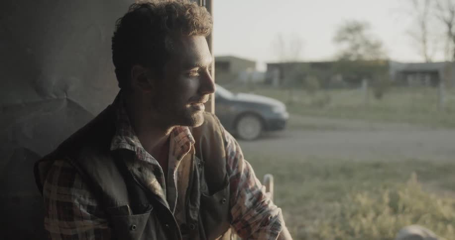 A male using a cell phone sitting outside near a dog