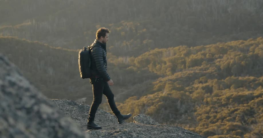 A man walking on a cliff overlooking the terrain