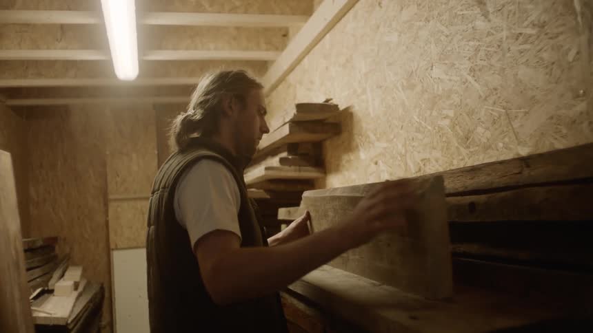 A man that is stacking some boards on a shelf