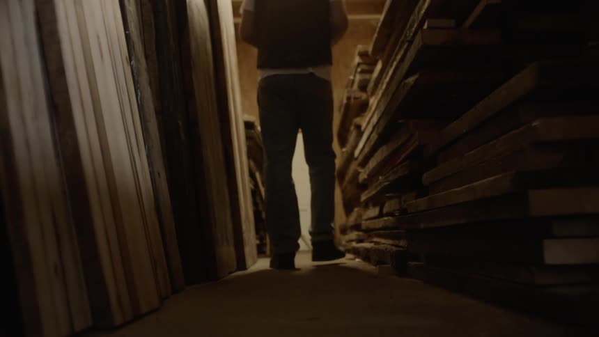 A man walks in the shed looking at lumber