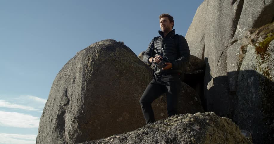 A man walking on a cliff with a camera in his hand