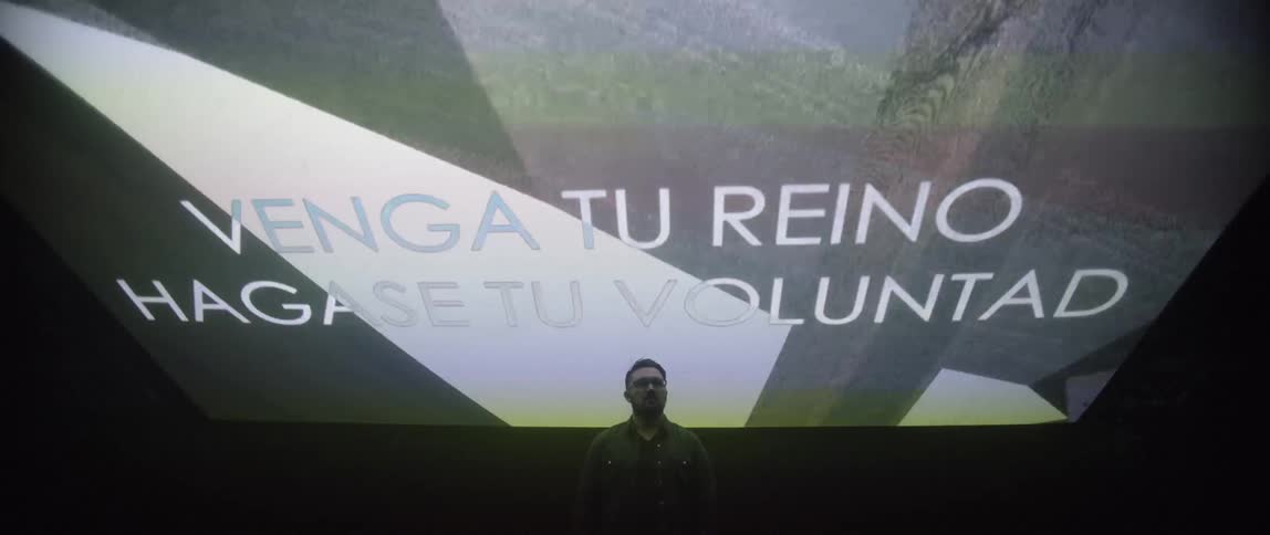 A man stands underneath a giant video screen