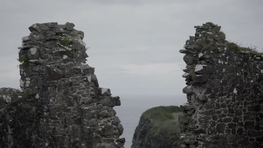 The partially standing stone walls of a large ancient monument on the coast