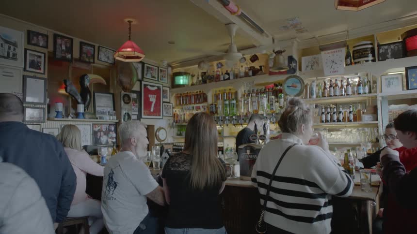 People sit at the bar of a pub and talk during daylight