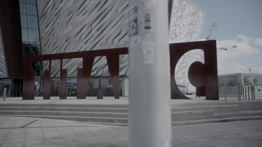A big artistic sign in front of large stylish building during the day
