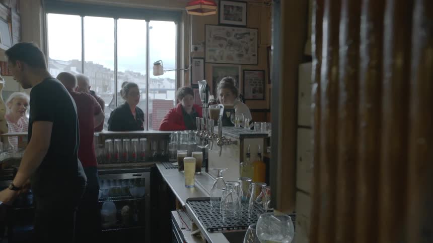A group of people sit at a counter in a restaurant
