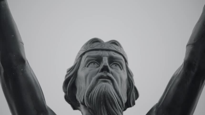 An outdoor statue of a bearded man with his arms raised wide