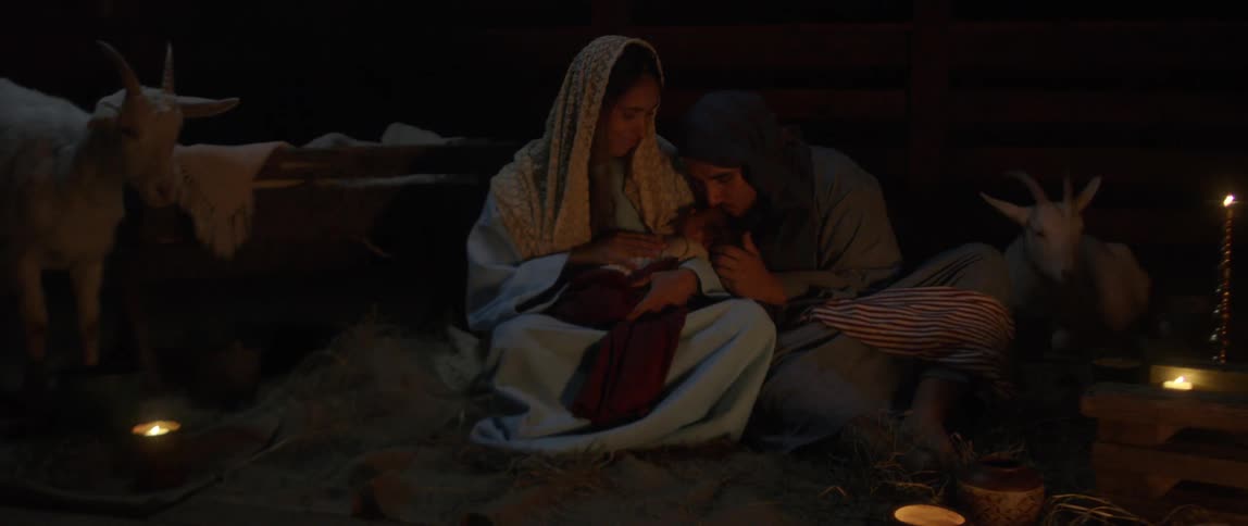 A woman sitting next to a fire while holding a baby