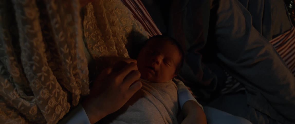A mother lovingly strokes the cheek of her newborn baby