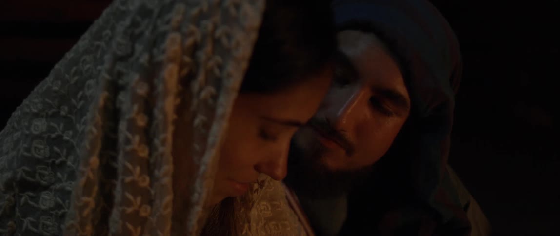 Man looks at woman while sitting by the fire at night