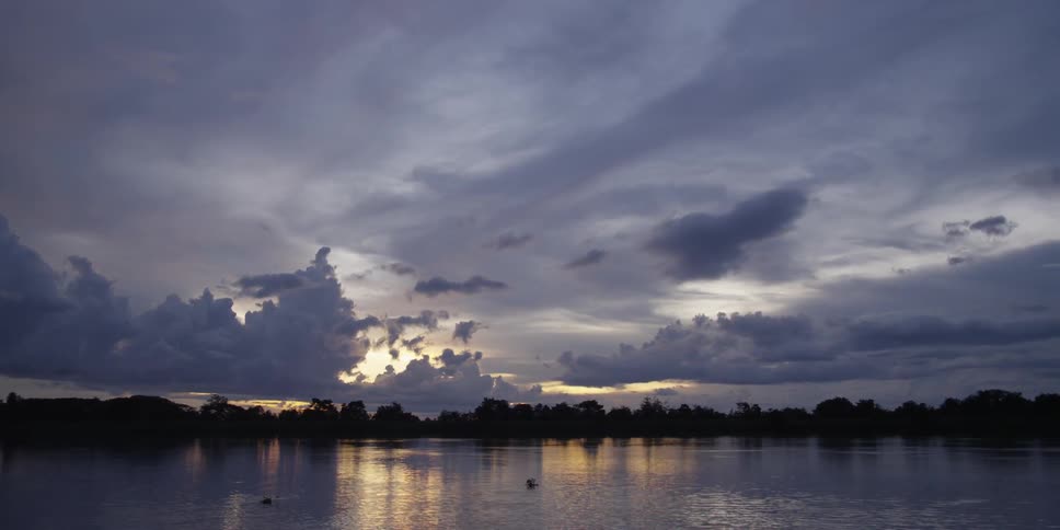 Sun setting behind clouds over a lake