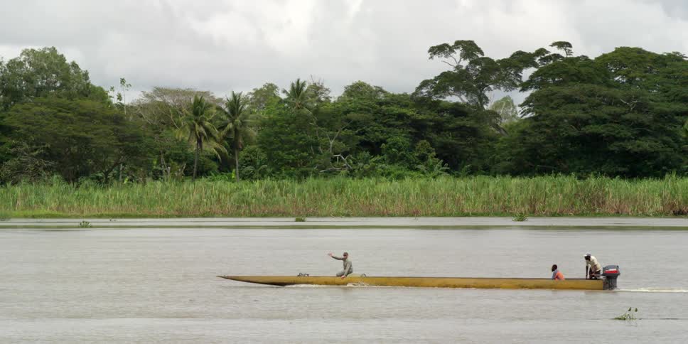Men in a long canoe on a river