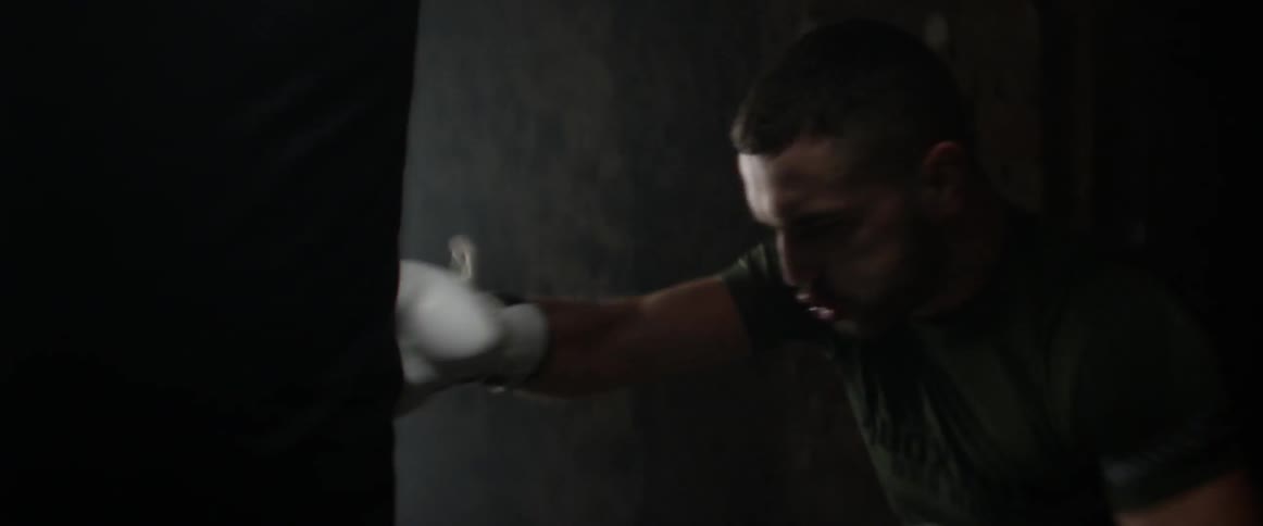 A man with boxing gloves on punches a bag