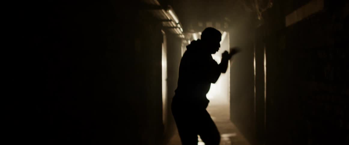 A boxer punches the air in a hallway with flashing lights