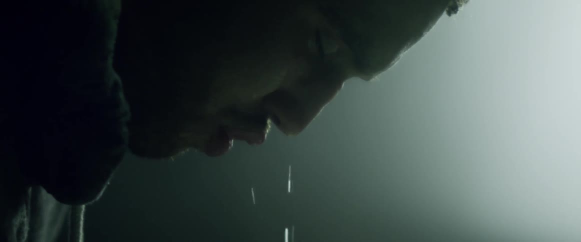 A person splashes water on their face from a sink