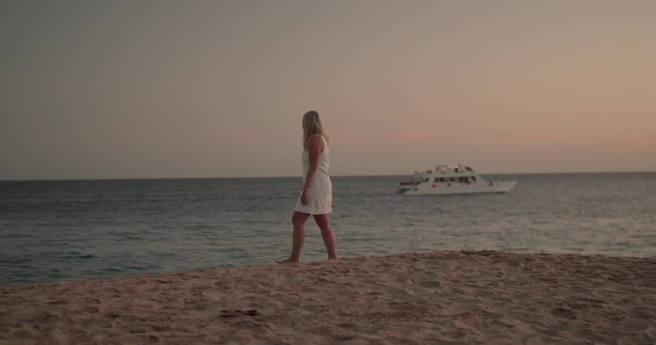 A woman is walking along the beach