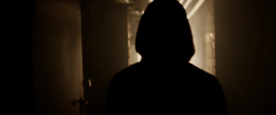 A person walks down a dark hall with flashing lights