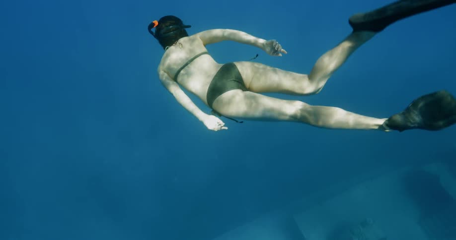 A woman with a snorkel swims over a shipwreck in the ocean