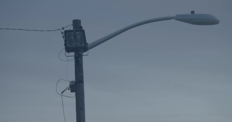 A street light with a power line attached on a cloudy evening