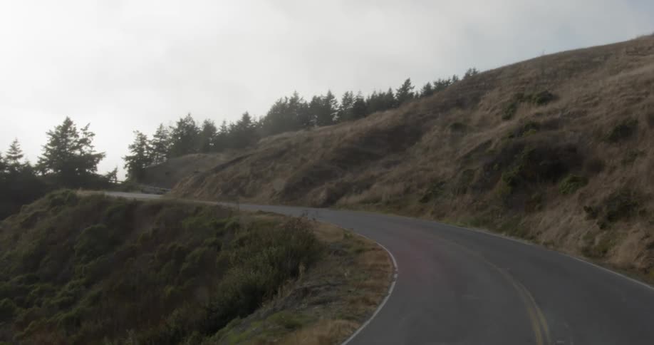 Rural road near hills under clouds