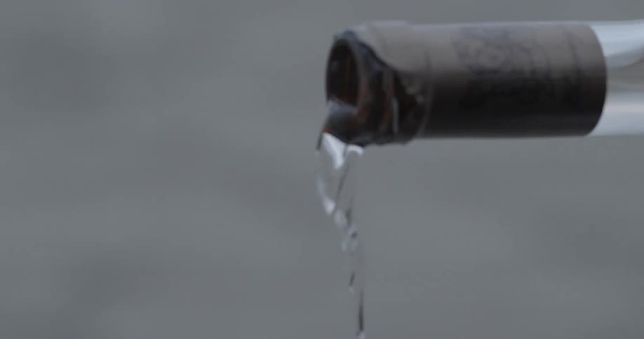 A clear liquor being poured from a bottle into a cup