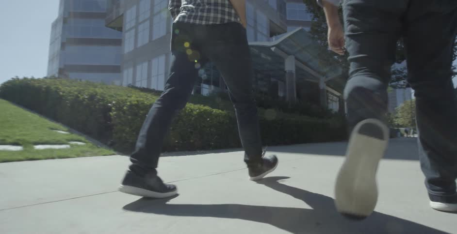 Two people walk along sidewalk
