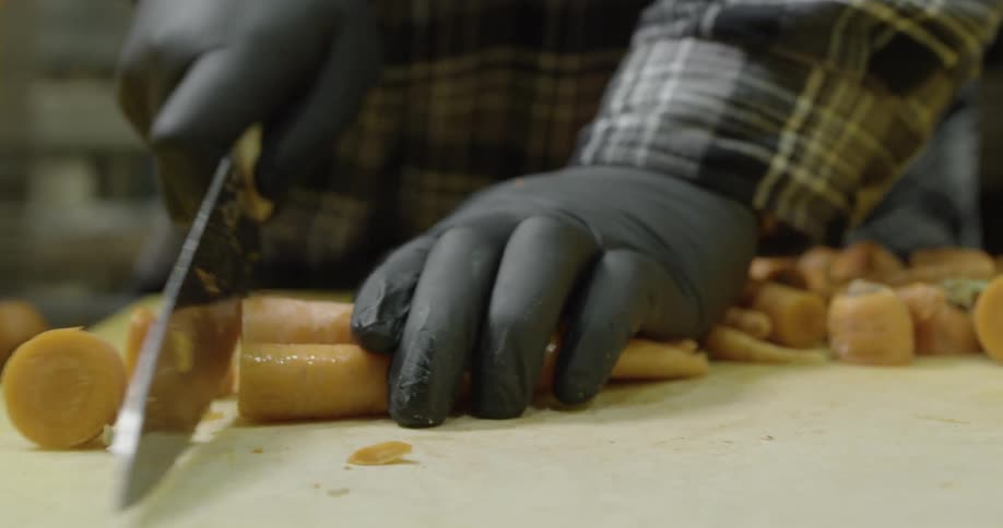 Person slices tops off of carrots on cutting board