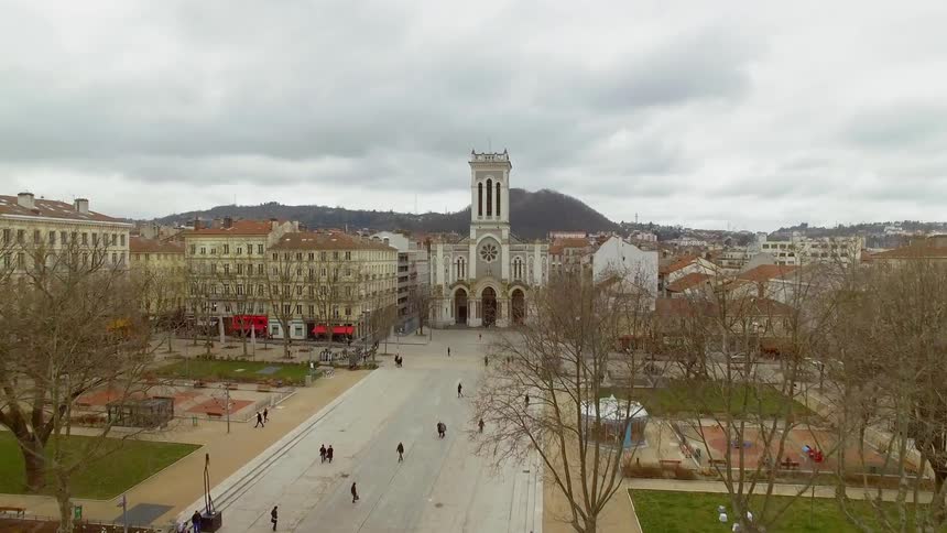 People walk down a broad plaza in the middle of buildings