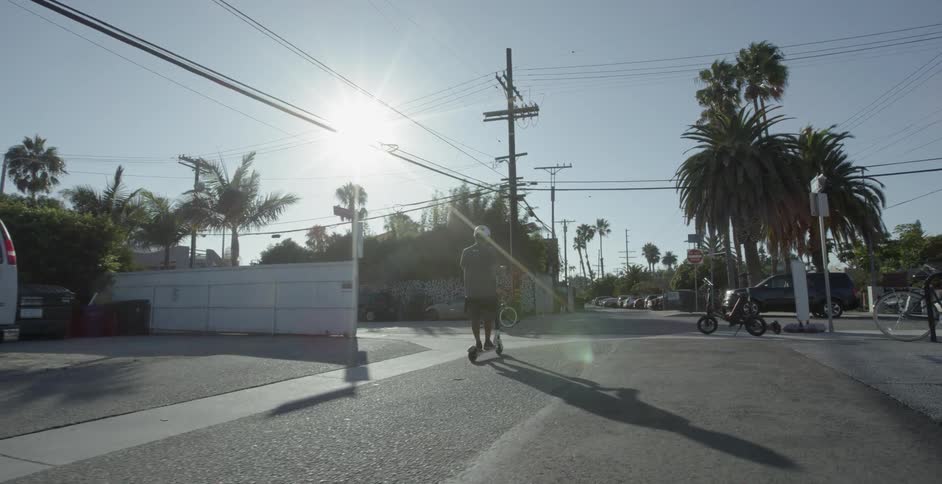 A couple children scooting and biking down a road